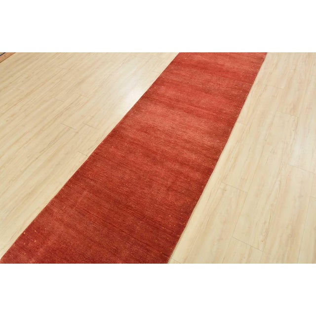 A contemporary Gabbeh runner hand-knotted with an all-wool pile on a cotton foundation. This oriental rug features a solid...