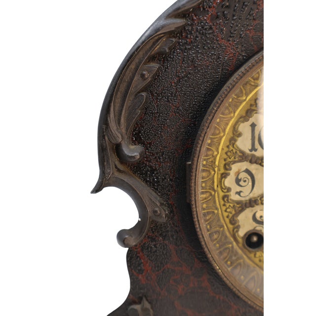 An expressive antique mantel clock with a sculptural wooden case, richly ornamented dial and dark, timeworn finish....