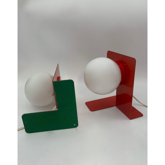 Table lamp with a minimalist and contemporary design, featuring a glossy white painted metal structure composed of a...