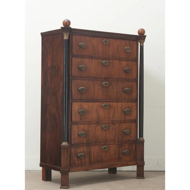Dimensions: 62” H x 44 ¼” W x 20 ¾” D A tall Dutch Empire style chest crafted from mahogany and ebonized wood, made during...