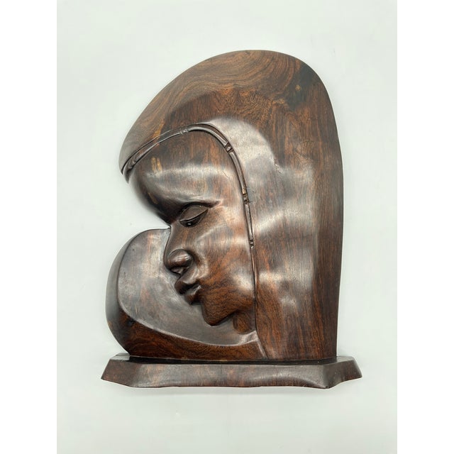 This expressive wall sculpture is crafted from dark Makassar ebony and depicts a stylized female portrait with softly...