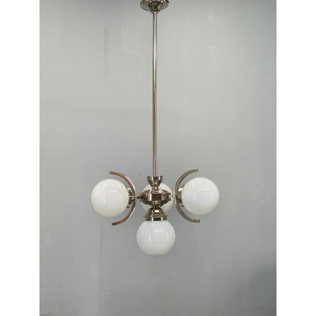 Art deco chandelier produced in 1930s czechoslovakia. This refined lighting fixture features a nickel-plated metal...
