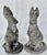 A charming pair of composition stone garden rabbits, each modeled seated upright with alert ears, tucked front paws, and...