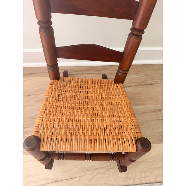 A charming vintage child’s rocking chair crafted from solid hardwood with a handwoven natural fiber seat. Features...