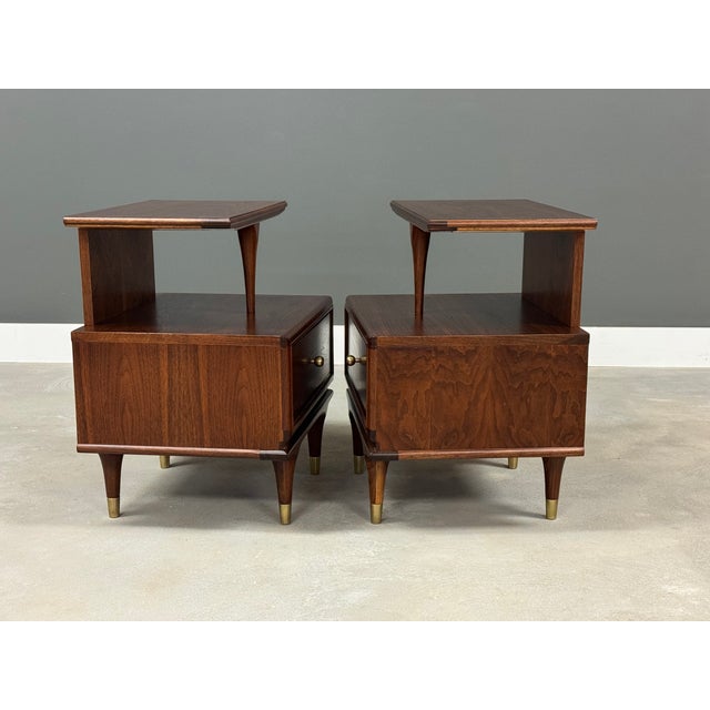 A pair of mid century modern walnut nightstands with a single drawer, polished brass knobb made by Kent Coffey...