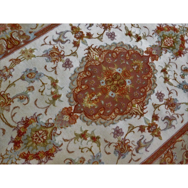 Ivory field with triple medallion, each with pendants on both sides. Floral border. Wool and silk pile. Soft color...