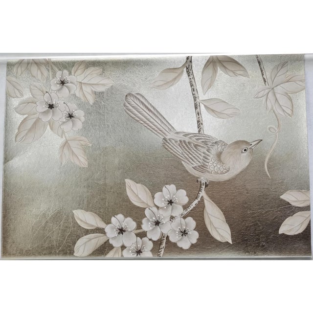 Elegant hand painted silver foil wallpaper sample featuring a delicate bird, blooming branches, and botanical leaves. The...