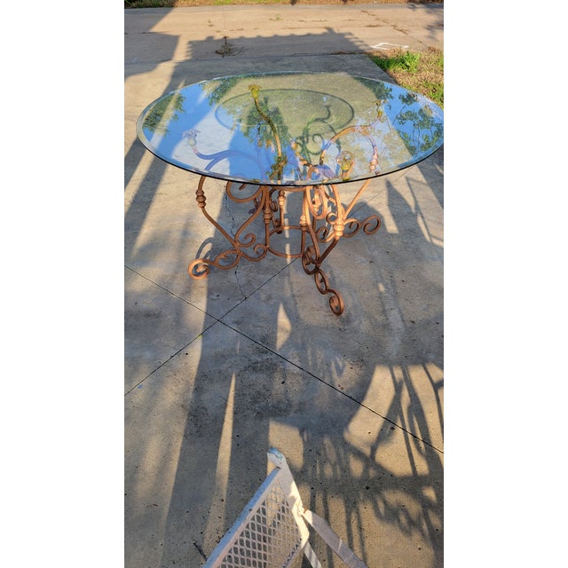 Beauiful vintage wrough iron table. The table has four ornate legs united on a circle at the center supporting a circular...