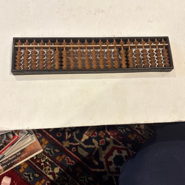 The image shows a soroban, which is a traditional Japanese abacus. This abacus is Meiji Era when one bead in the upper...