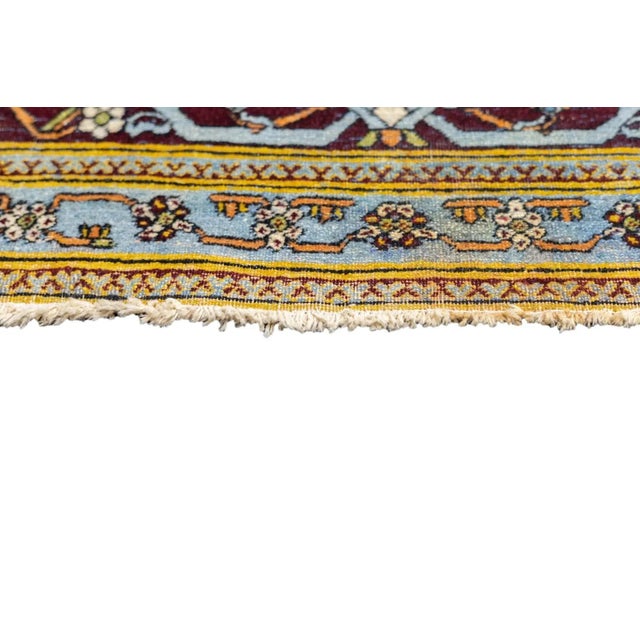 Three levels of arabesques, the primary one in green, decorate the ecru field. The tall navy medallion shows pendants...