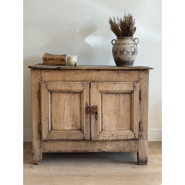 This antique French oak sideboard features solid oak construction, two paneled doors, original iron latch hardware, and a...