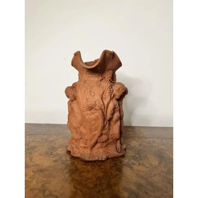 Large antique quality relief moulded terracotta jug modelled in relief images of Bacchus with a shaped handle to the back....