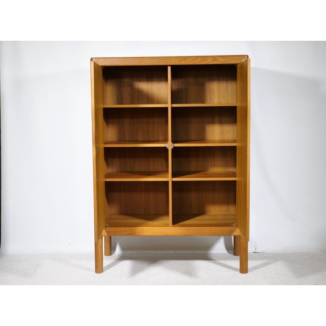 Danish Design teak highboard by Bramin, 1960s. A tall cabinet with two doors, round inset wooden handles, and softly...