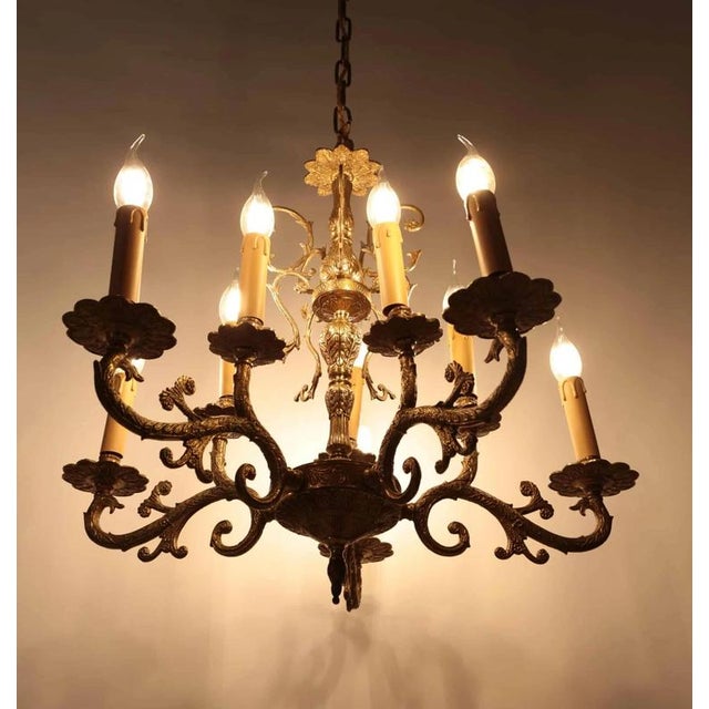 Richly decorated chandelier made of polished brass in the Rococo style with five decorated arms from which plant tendrils...