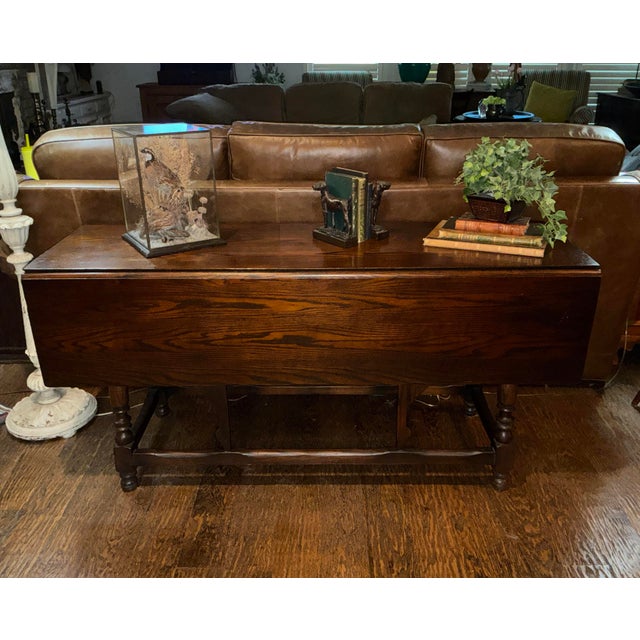 This is a vintage antique drop-leaf sofa table sometimes referred to as a console table. It features hinged side panels...
