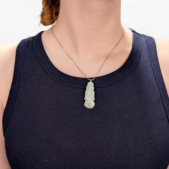 A fine vintage gold & jade pendant. In 14 karat yellow gold. With a prong-set carved jadeite drop with a double loop bail...
