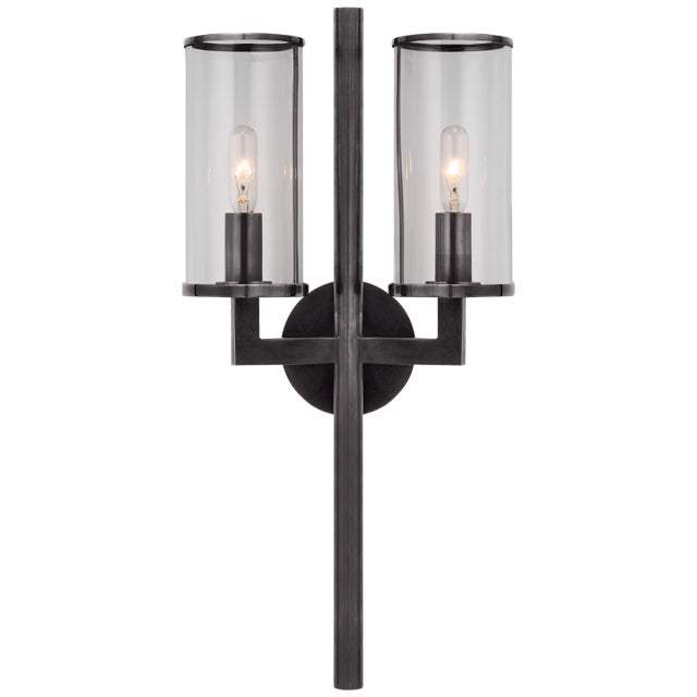 Liaison Double Sconce in Bronze with Clear Glass Designer: Kelly Wearstler Height: 19" Extension: 5.25" Backplate: 4"...