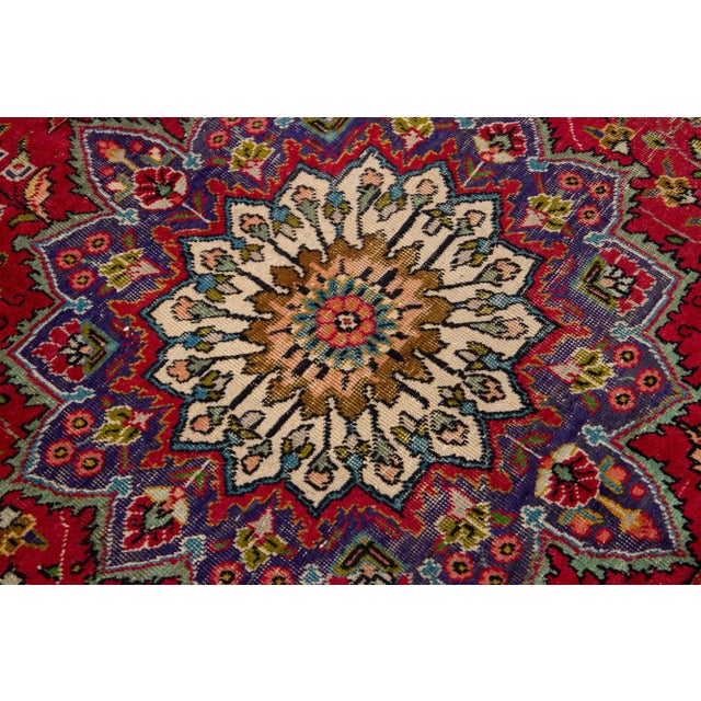 Beautiful vintage Persian Tabriz hand-knotted wool rug with a red color field. This piece has a navy blue frame and...