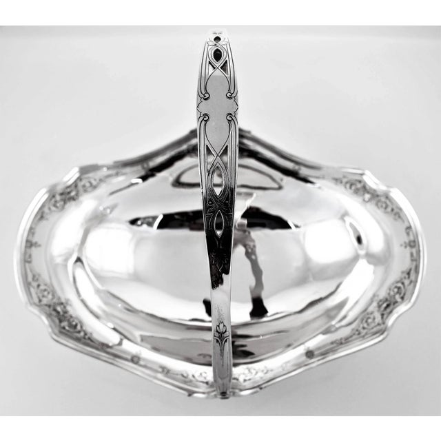 This basket has pretty etched work around the edge. There’s a scalloped rim that is also fluted. It has a movable handle...