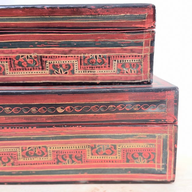 A finely worked antique lacquerware box in deep red, black, and gold, the lid decorated with a grid of roundels depicting...