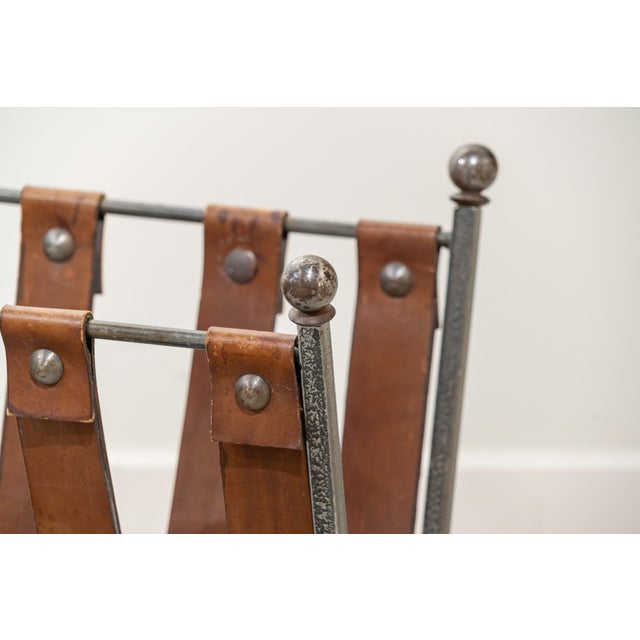 Wrought iron magazine rack in a "U" shape with natural leather straps. Attractive patina on the metal and leather.