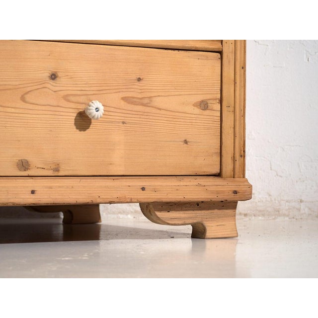 This antique solid pine chest of drawers embodies early 20th century rural European furniture, designed for everyday use...