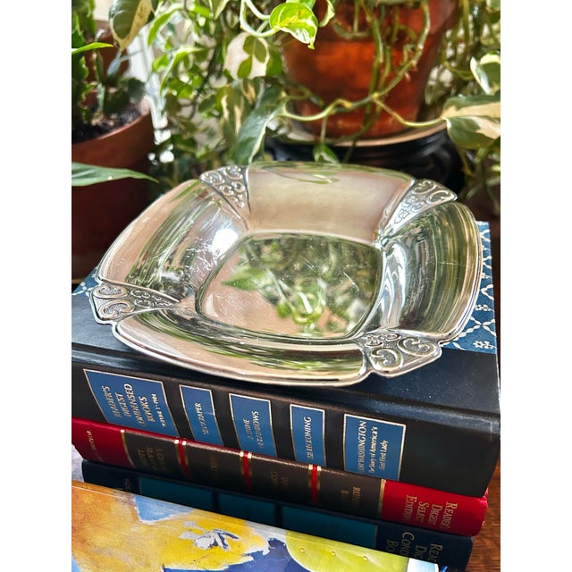 By International Silver, this silver plate dish is of the pattern called “Triumph”. It is 6.5” square and features corners...