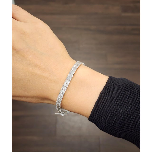 This refined tennis bracelet showcases a modern aesthetic. It features a continuous line of 51 natural emerald-cut white...