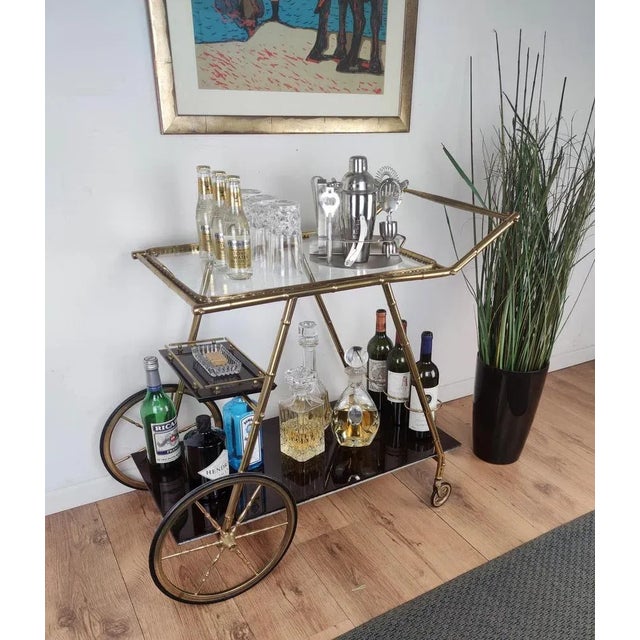 Beautiful and stylish vintage 1970s Italian two-tier brass and glass bar cart with removable top tray, great brass wheels...
