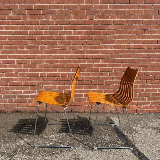 Pair of Hans Brattrud “Scandia” chairs for Hove Møbler, Norway, with sculptural bent teak slats and chrome sled bases. The...