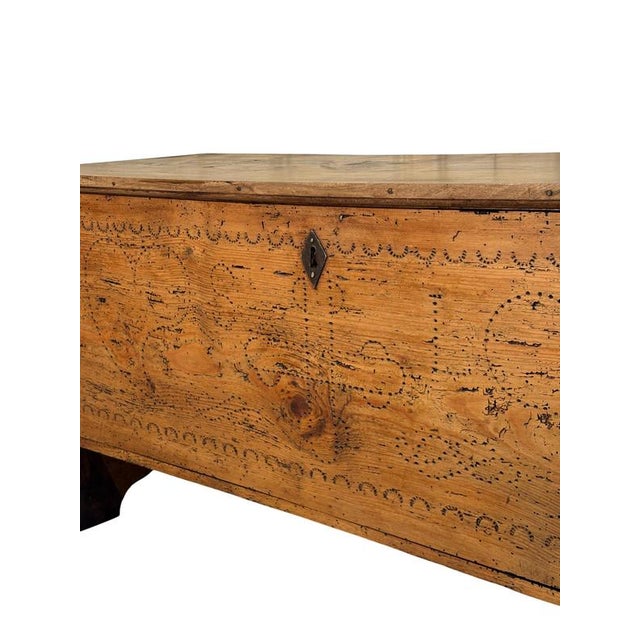 A rustic 19th-century fir wood chest, characterized by richly detailed craftsmanship and engraved decorations that testify...