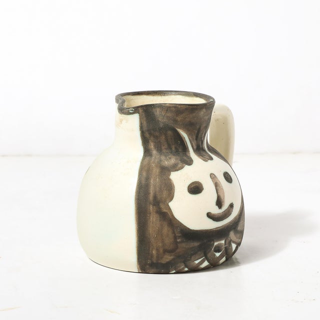 This Madoura Pottery glazed earthenware Têtes pitcher, signed by Pablo Picasso and created in France circa 1953,...