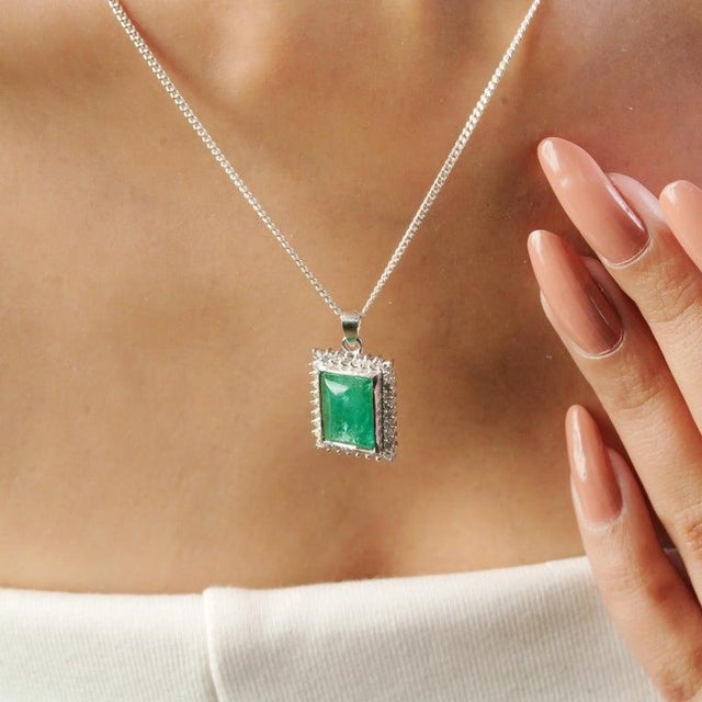 A refined expression of elegance, this 925 sterling silver pendant features a striking rectangular emerald weighing 4.9...