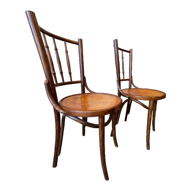 Pair of Thonet bentwood cafe chairs. The seats feature spindle backs and a detailed iris motif framed by the classic...