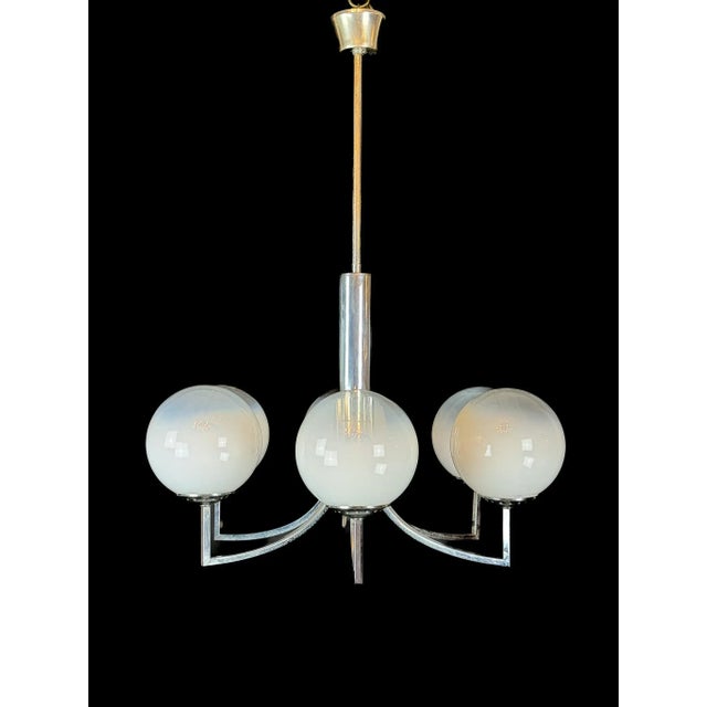 Elegant six-arm chandelier featuring hand-blown Murano glass spheres mounted on a polished chrome structure. The white...