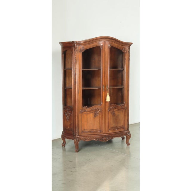 Louis XV Style Carved Walnut Stained Vitrine Armoire This vitrine is a lovely example of the Louis XV style, with a bonnet...