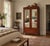 This antique wardrobe armoire features mirrored doors beneath a shaped scroll crest, all finished in a warm red-brown...