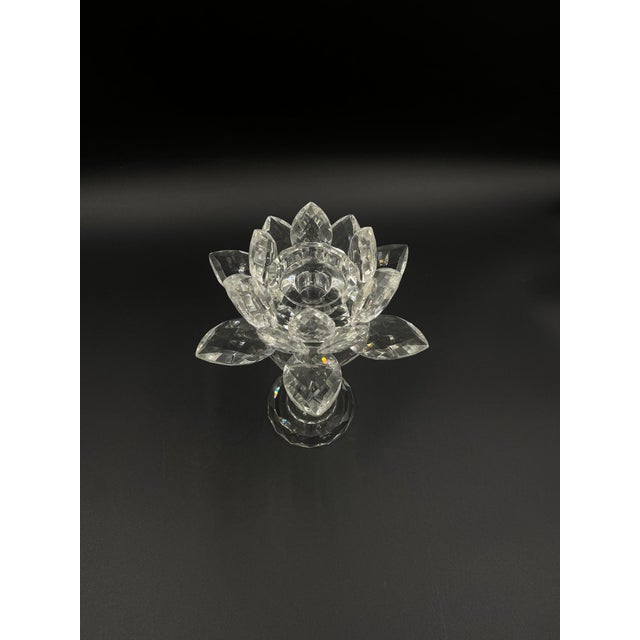 A decorative vintage crystal candle holder in the shape of a lotus flower, set on a tall, slender stem. The upper part of...