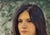 This portrait captures a young Mexican girl with a serene expression, her gaze directed thoughtfully outward. The vibrant...