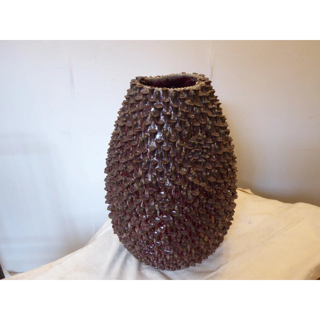 Hand sculpted celadon ceramic vase in tones of brown, deep red, and gray.