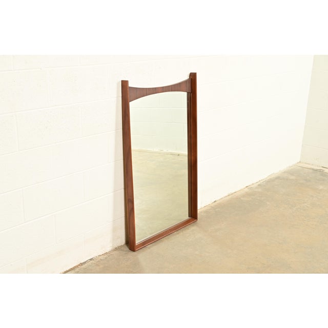 A beautiful Mid-Century Modern sculpted walnut and rosewood framed wall mirror In the manner of Broyhill Brasilia By Kent...