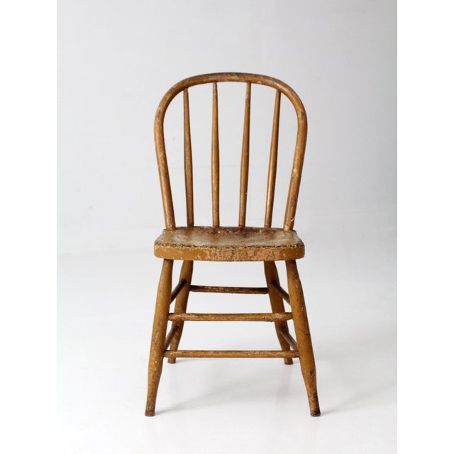 This antique American Windsor chair dates to the late 19th century and features a continuous bow back, turned spindles, a...