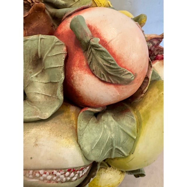 Large beautiful Italian ceramic fruit compote in faux wicker basket showcasing a collection of oranges, apples, pears,...