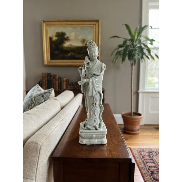 Exquisitely rendered in a luminous pale off white glaze, this graceful porcelain figurine depicts a serene celestial...