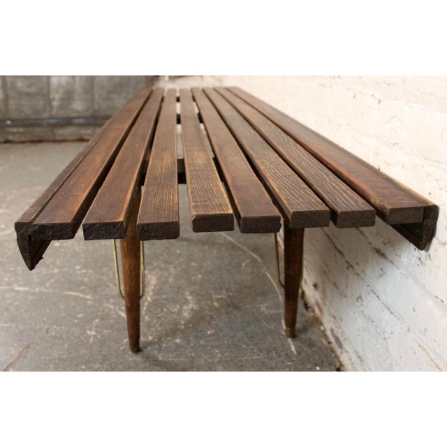 A timeless Mid-Century Modern walnut slat bench featuring a sleek, minimalist design with solid walnut construction and...