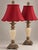 A matched pair of neoclassical table lamps with tall, fluted urn bodies in a cream crackle finish. Sculpted bronze-tone...