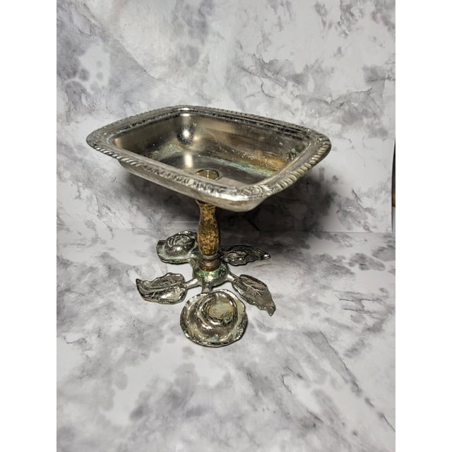 This is a vintage pedestal soap dish and looks to be silver plate and brass. The base features leaves and roses.