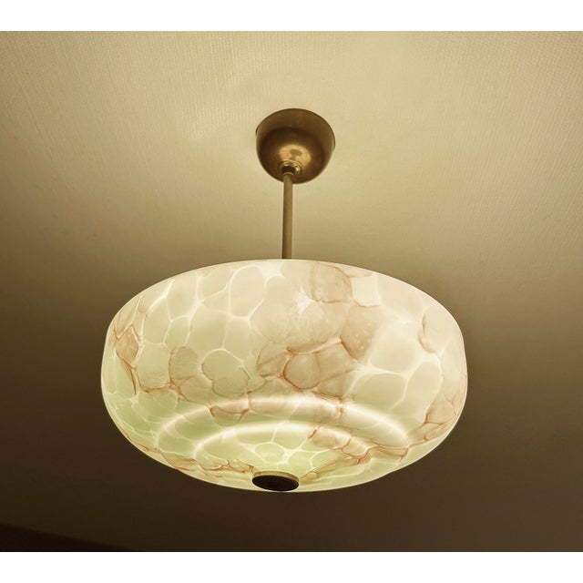 Art Deco pendant lamp with a green mottled marble glass shade with darker veins and patches, burnished brass holder and...