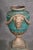 A pair of verdigris painted iron garden urns with bearded face and garland motif.