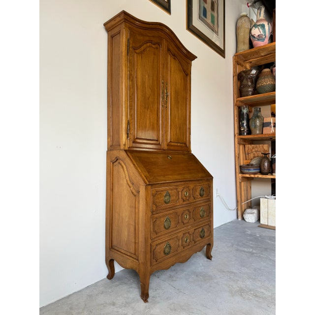 The upper cabinet showcases serpentine doors with intricate brass foliate keyplates and opens to reveal two adjustable...